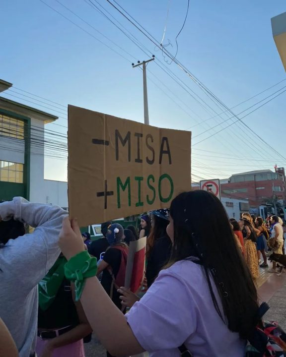 Mujer levanta cartel que dice "-Misa +Miso"