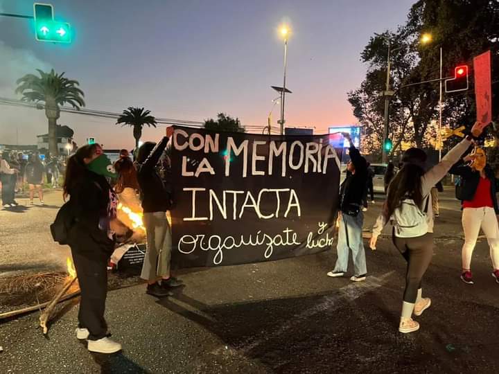 Dos mujeres levantan un lienzo que dice "Con la memoria intacta organizate" 